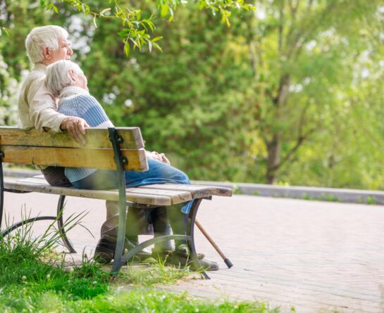 mature couple sitting on wood park bench
