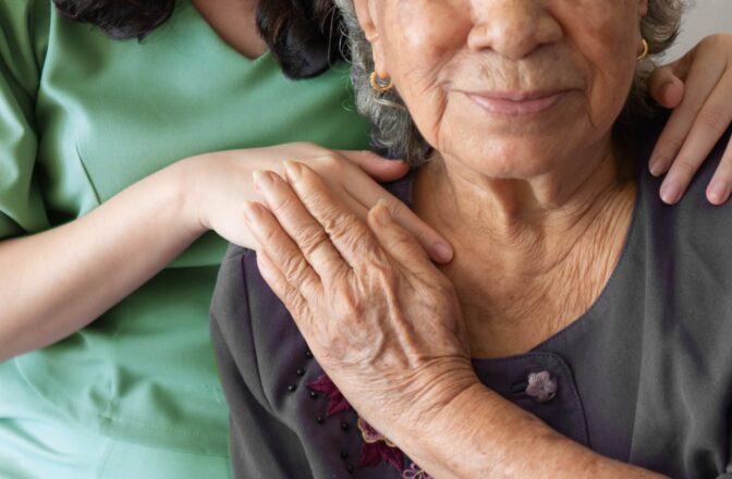 mature woman and caregiver touching hands