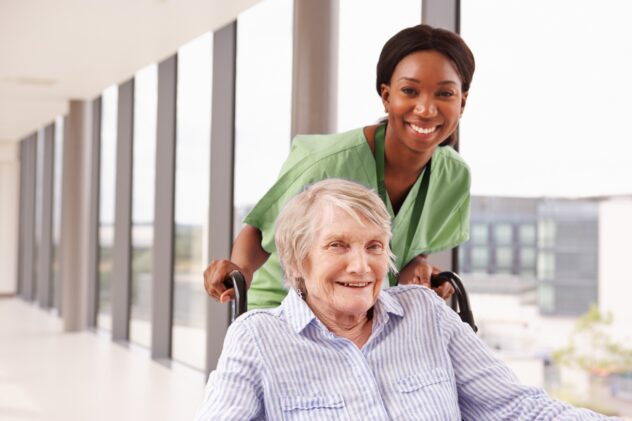 mature person in wheelchair being helped by professional caregiver