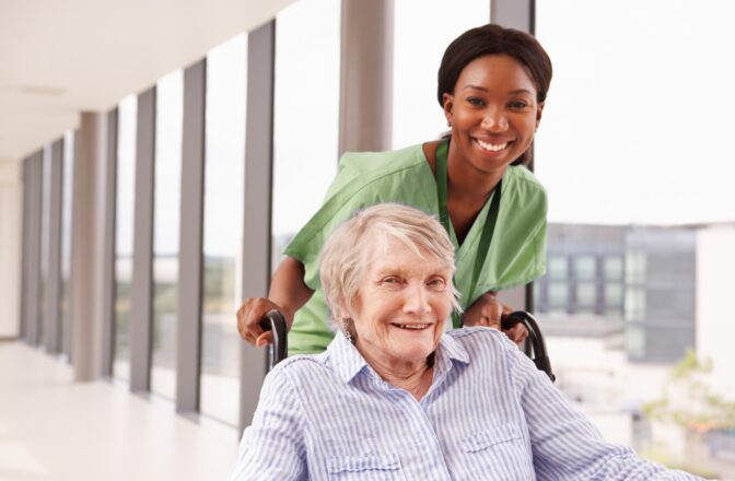 mature person in wheelchair being helped by professional caregiver