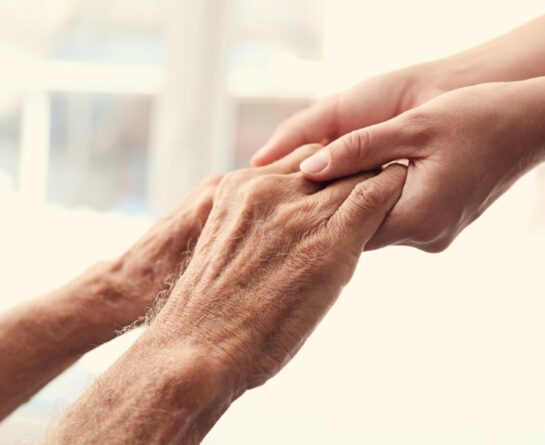 Male senior's hands holding younger female's hands