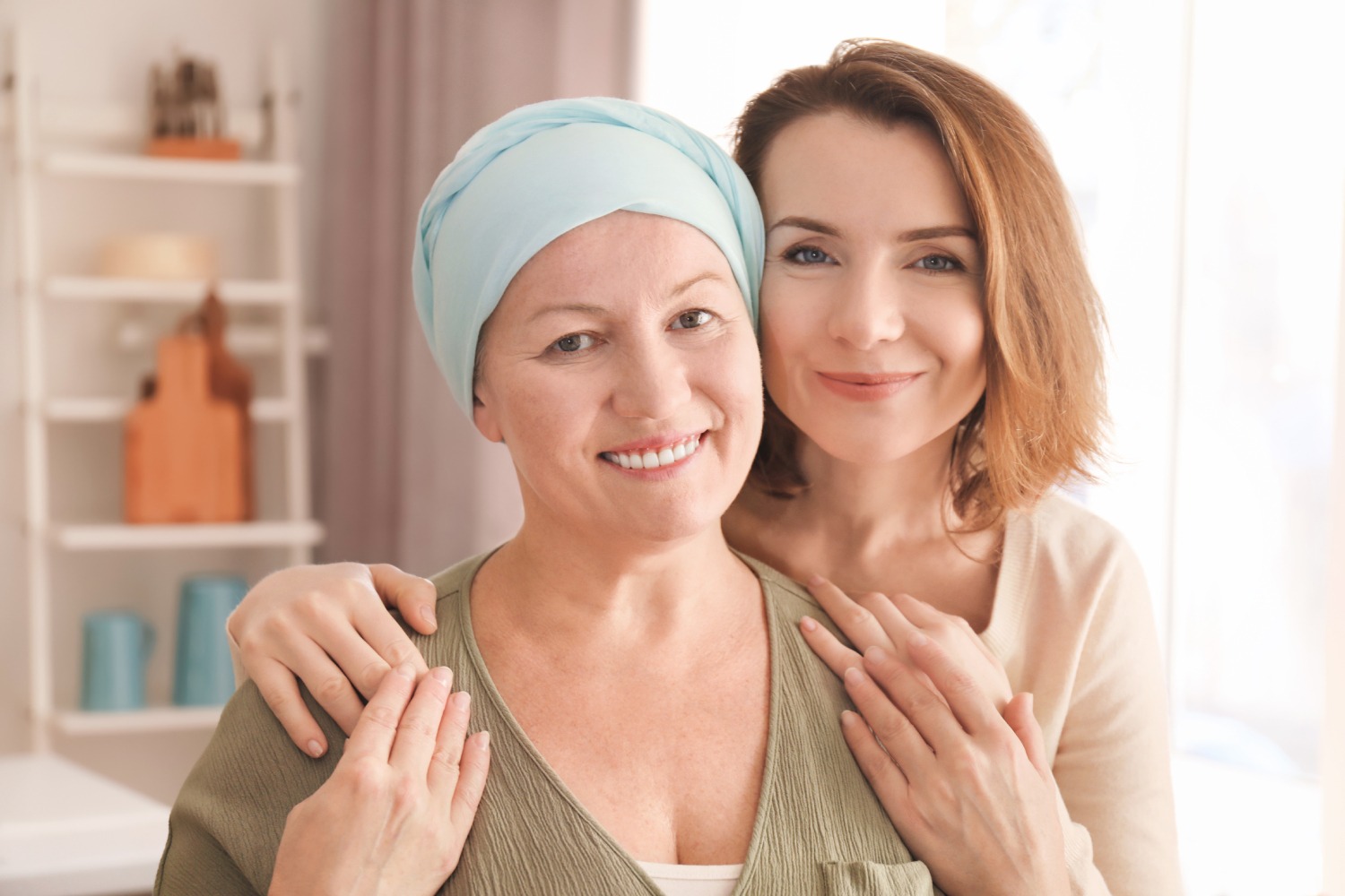 Female women smile at the camera as one of them hugs the other from the back