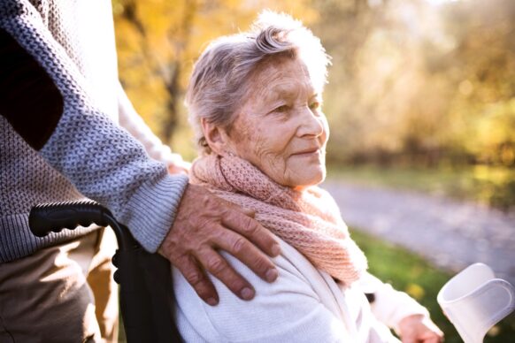 mature woman in wheelchair with mature man's hand on her shoulder