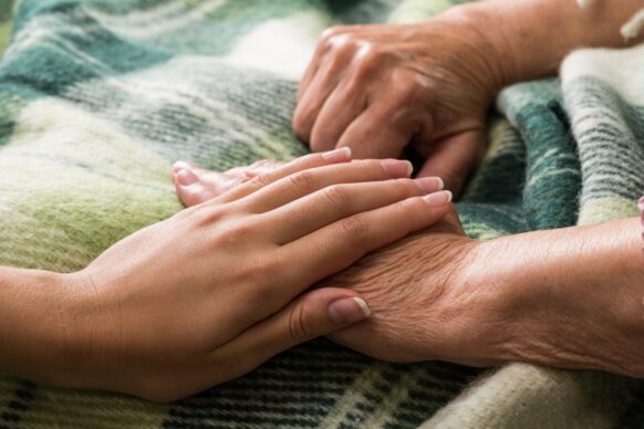 young woman's hand on top of elderly persons hand