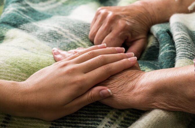 young woman's hand on top of elderly persons hand