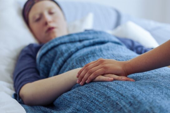 patient lying in bed being consoled by other