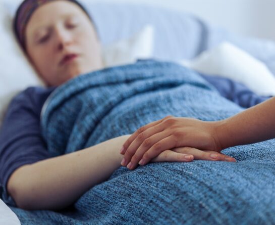 patient lying in bed being consoled by other