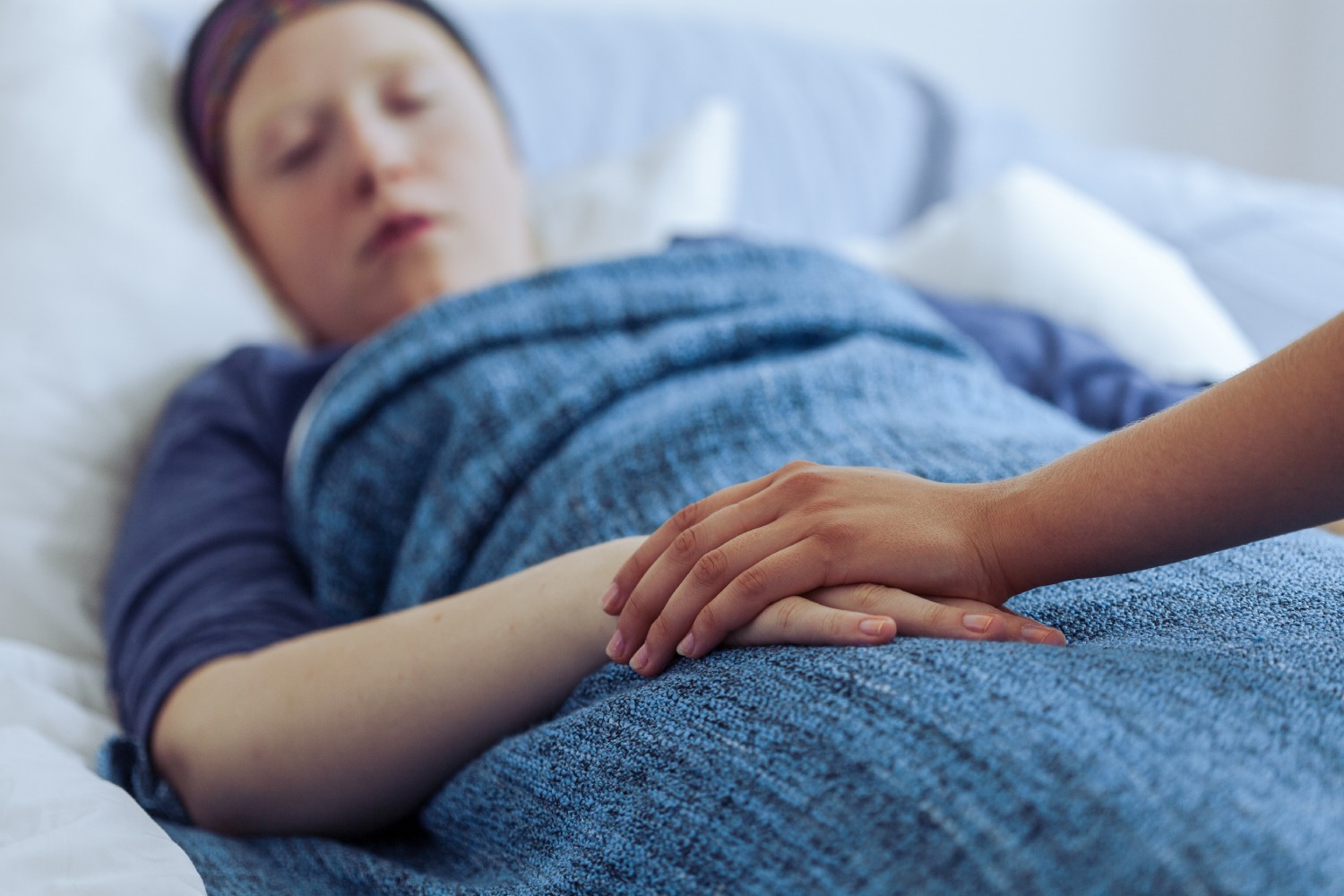 patient lying in bed being consoled by other