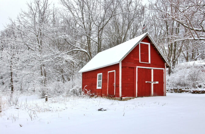 winter scene of small red barn and trees covered in snow