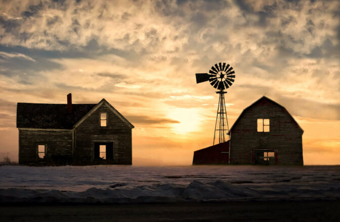 winter scene of house and barn with windmill at sunset