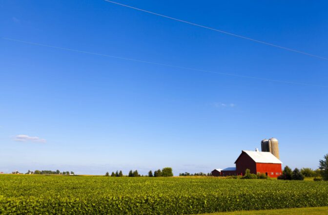 open blue sky and agriculture land with red bar and grain silos