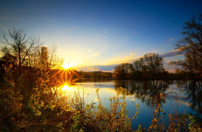 view of lake from shore at sunset