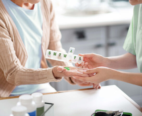 Nurse giving pills from clear, pill organizer to senior woman
