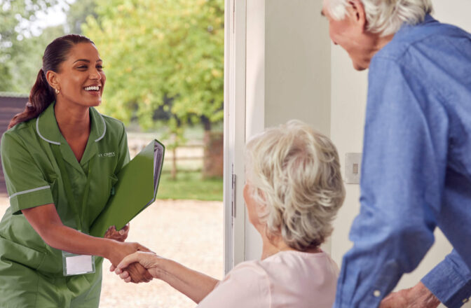 Nurse greeting senior woman in wheel chair while male senior carries her