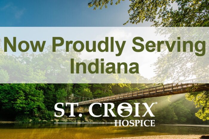 Text informing that St. Croix Hospice now serves Indiana area with wooden bridge crossing a lake as background