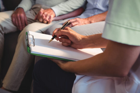 Nurse fills out paper work while senior father holds son's hand