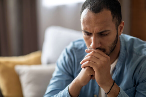 Male thinking with fist shaped hands over his mouth