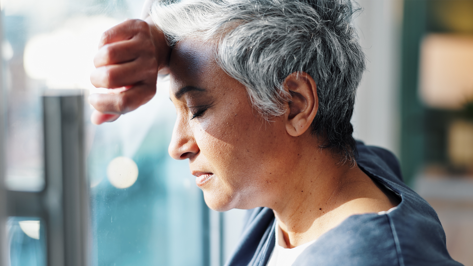 Burned out caregiver leaning on window