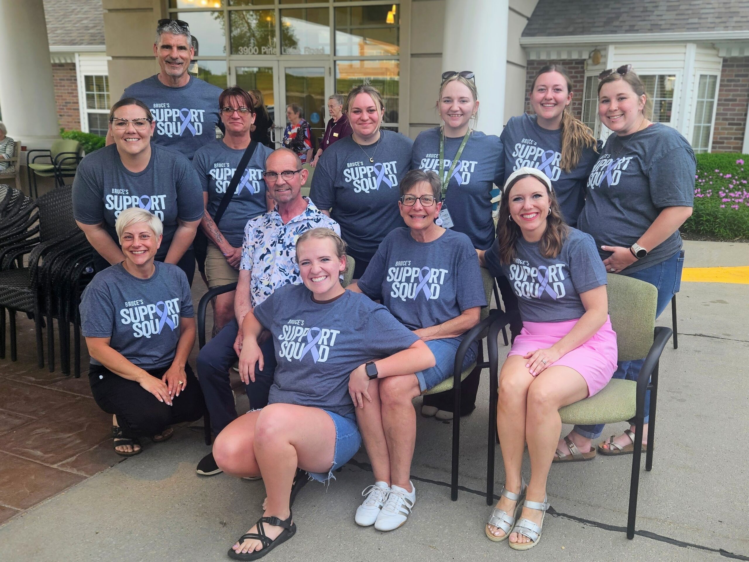 Man sitting in chair surrounded by people with matching t-shirts