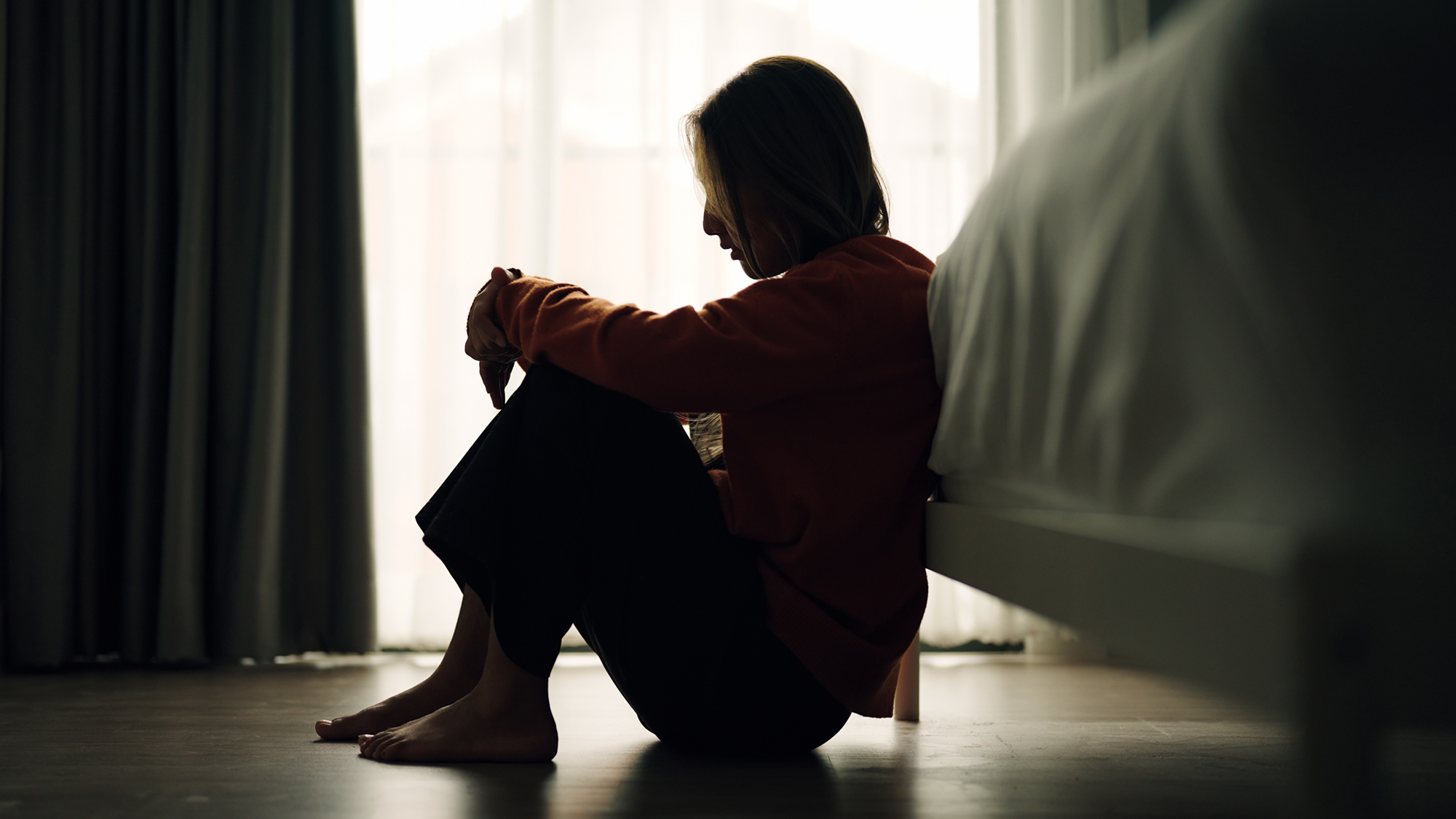 grieving woman sitting next to bed alone
