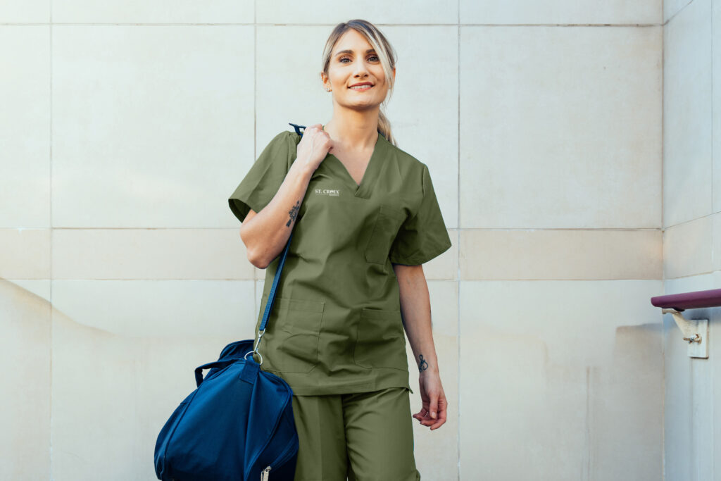 nurse with green scrubs and blue duffle bag smiling